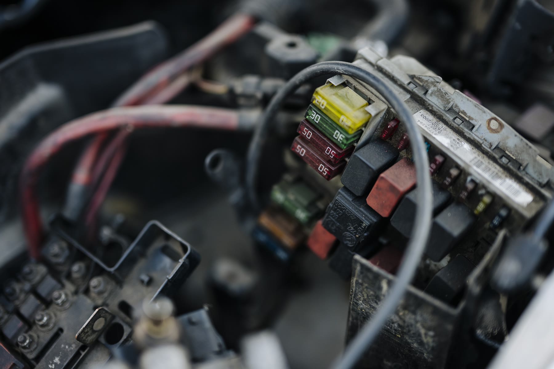 Caixa de fusíveis no motor de um carro, com fusíveis e relés coloridos entre os fios